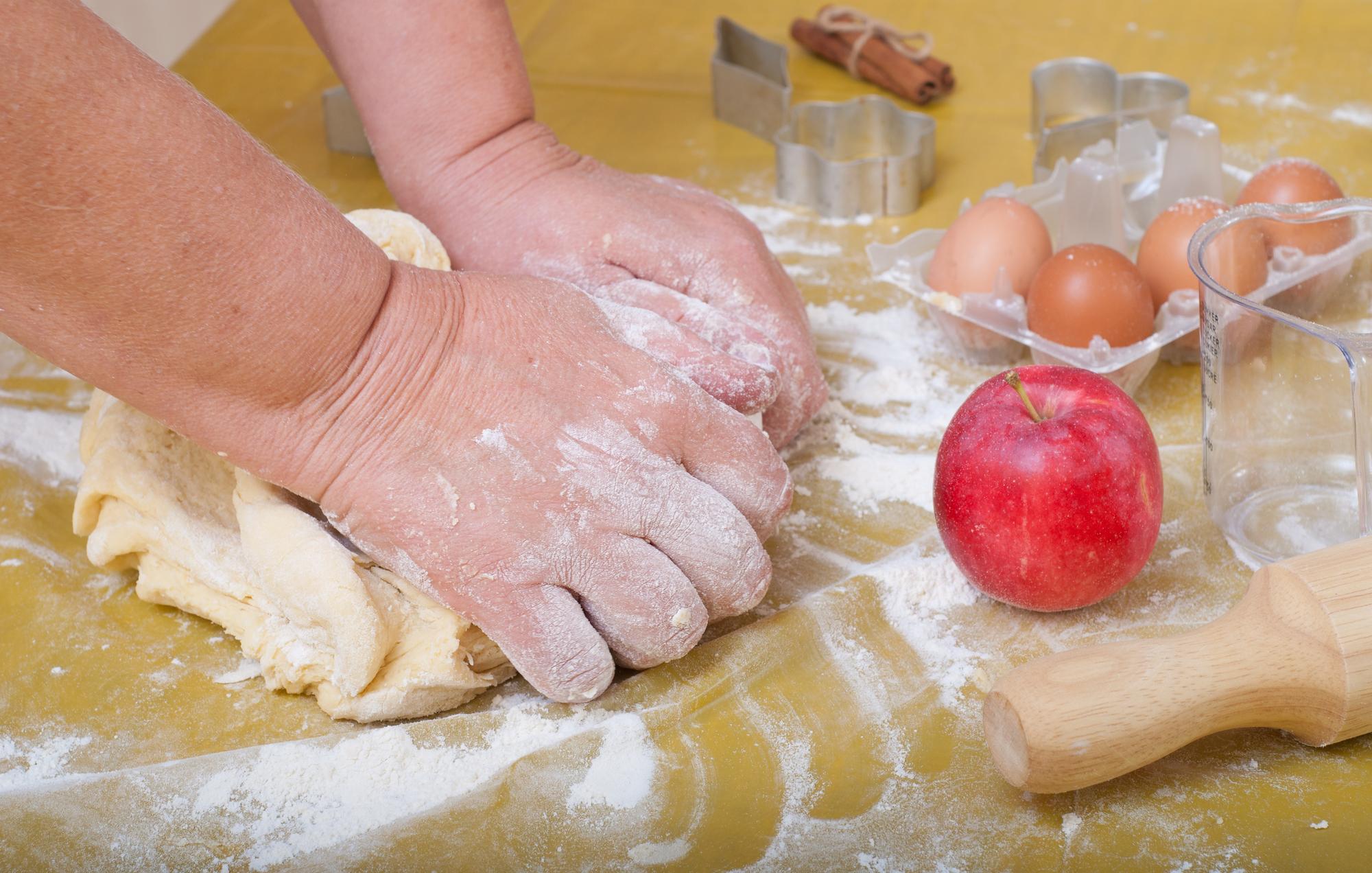Hands kneading dough in bright kitchen